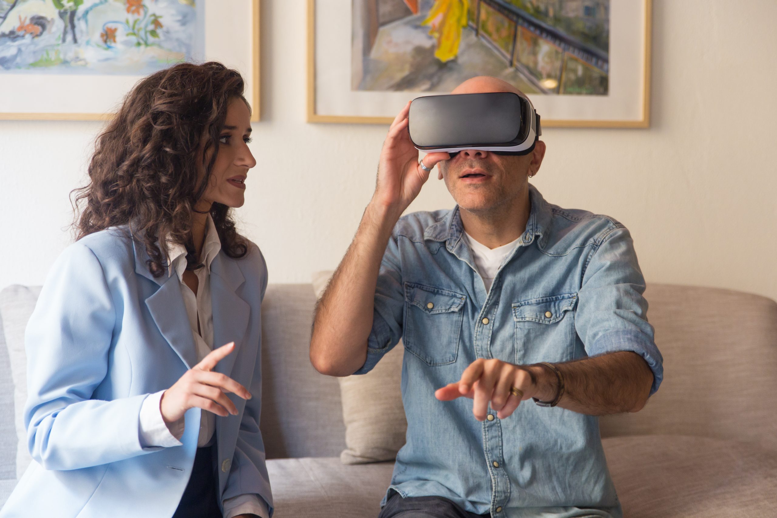 Young woman instructing man wearing VR headset